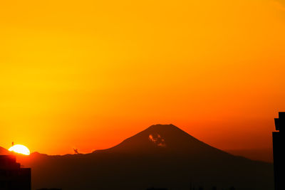 Scenic view of silhouette mountains against orange sky