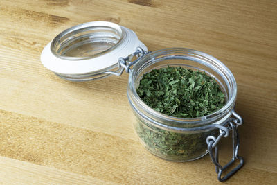 A jar of dried parsley on a wooden table