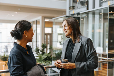 Smiling female business professionals discussing during networking event at convention center