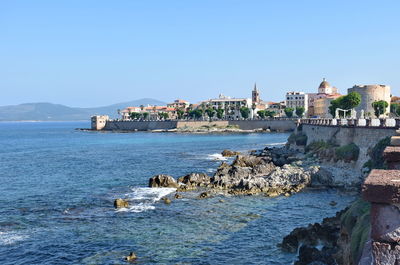 Sea by buildings against clear blue sky