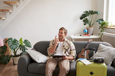 Young woman using phone while sitting on sofa at home