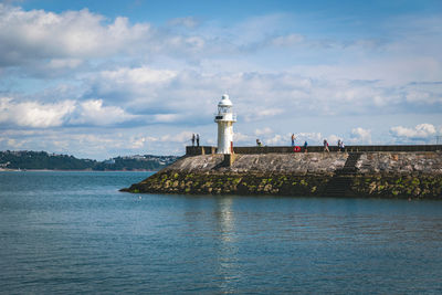 Lighthouse by sea against sky