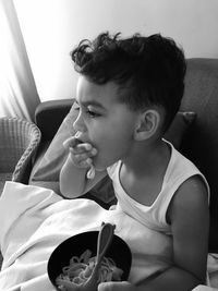 Close-up of boy eating pasta while sitting on sofa at home