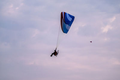 Man paragliding against sky during sunset