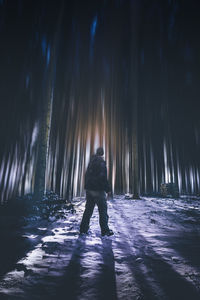 Rear view of silhouette man standing on snow covered landscape