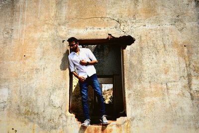 Young man standing on damaged window on abandoned building