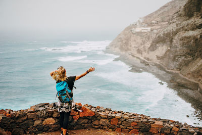 Rear view of man standing on rock by sea
