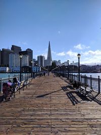 Footpath leading towards buildings against sky