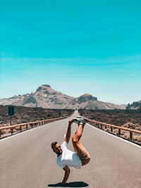 Full length of woman on road against blue sky