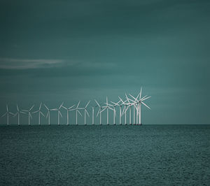 Wind turbines in sea against sky