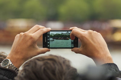 Midsection of man photographing with mobile phone