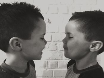 Cute twin brothers standing against brick wall