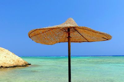 Traditional windmill on beach against clear blue sky