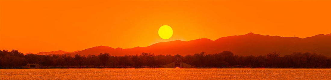 Scenic view of silhouette mountains against orange sky