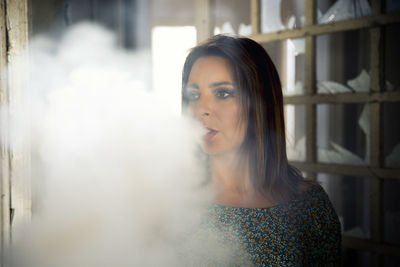 Thoughtful woman exhaling smoke