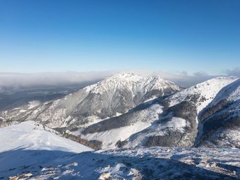 Scenic view of snowcapped mountains against clear blue sky