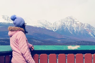 Rear view of woman looking at snowcapped mountain against sky