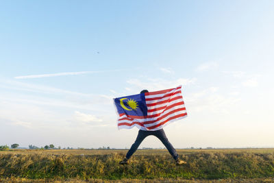 Flag flying over field against sky