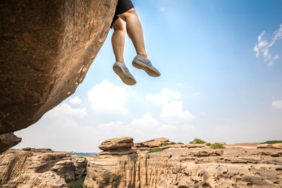 Rear view of man on rock formation against sky