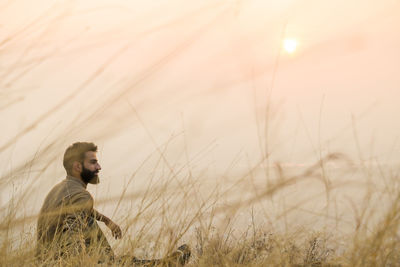 Side view of man standing on field in golden sunlight 