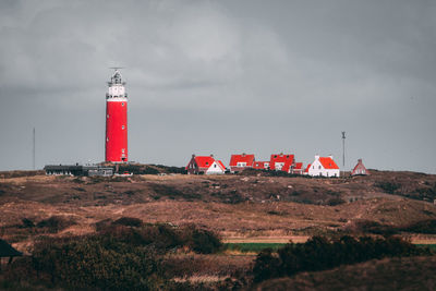 Lighthouse by building against sky