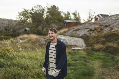 Portrait of cheerful mid adult man standing at island during summer vacation