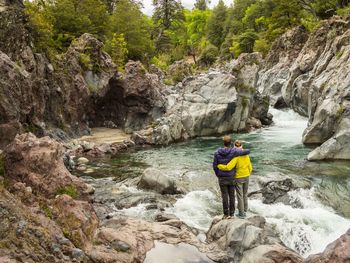 Man surfing on rock by river