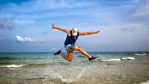 Man jumping in sea against sky