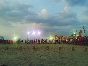 People on beach against cloudy sky