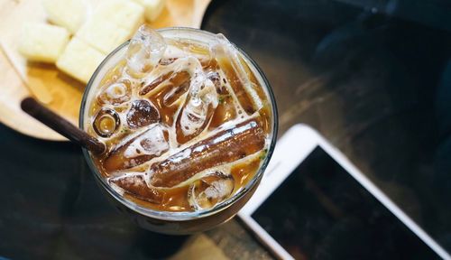 High angle view of iced cooling and mobile phone on table