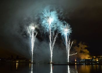 Firework display over river against sky