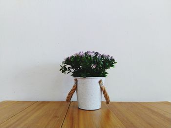 Flower vase on table against wall