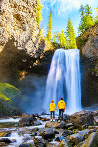 Rear view of man standing against waterfall