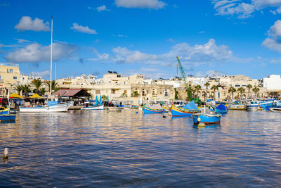 Boats moored at harbor against blue sky