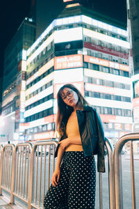 Portrait of smiling young woman standing against building in city