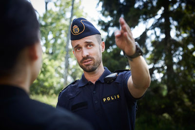 Male police officer gesturing while directing woman outdoors