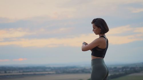 Side view of young woman exercising at beach