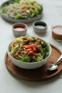 High  angle view of indonesian spicy salad, topped with peanut sauce on the table.