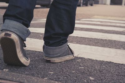 Low section of man walking on zebra crossing