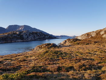 Scenic view of sea and mountains against clear blue sky