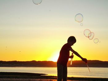 Silhouette of woman jumping at sunset