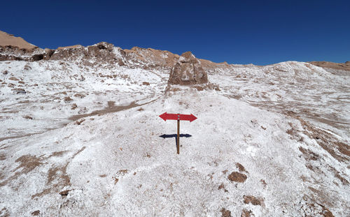 Low angle view of road sign on mountain against clear sky