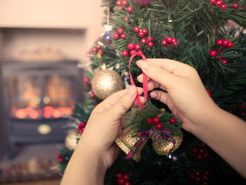 Cropped image of hands decorating christmas tree