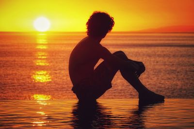 Rear view of silhouette woman standing at sunset