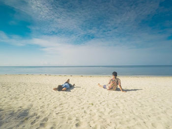 People sitting on beach against sky