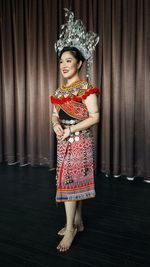 Portrait of woman standing against curtain