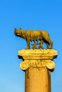 Low angle view of old sculpture against clear blue sky