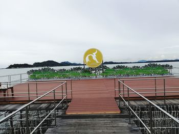 Yellow railing by staircase against sky