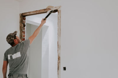 A man working with a crowbar in a doorway.