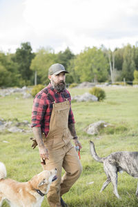 Male farmer walking with dogs in field